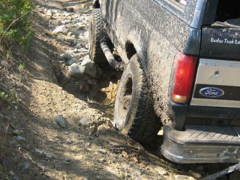 1995 Ford Bronco - Mud-covered 1995 Ford Bronco navigates a challenging rocky and muddy off-road path.