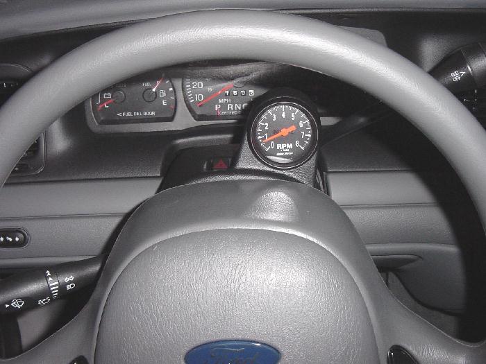 Ford steering wheel and instrument cluster with aftermarket tachometer mounted on column