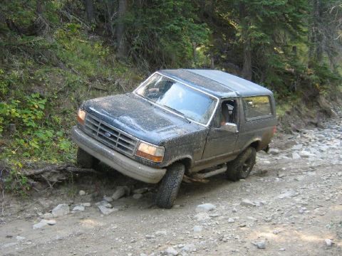 1995 Ford Bronco - This 1995 Ford Bronco is shown off-road on a rough, rocky path surrounded by trees.