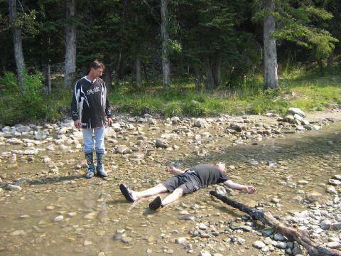 1995 Ford Bronco - One man lies in a rocky stream while another stands nearby, observing.