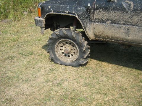 1995 Ford Bronco - Close-up of a muddy off-road tire and the front fender of a vehicle.