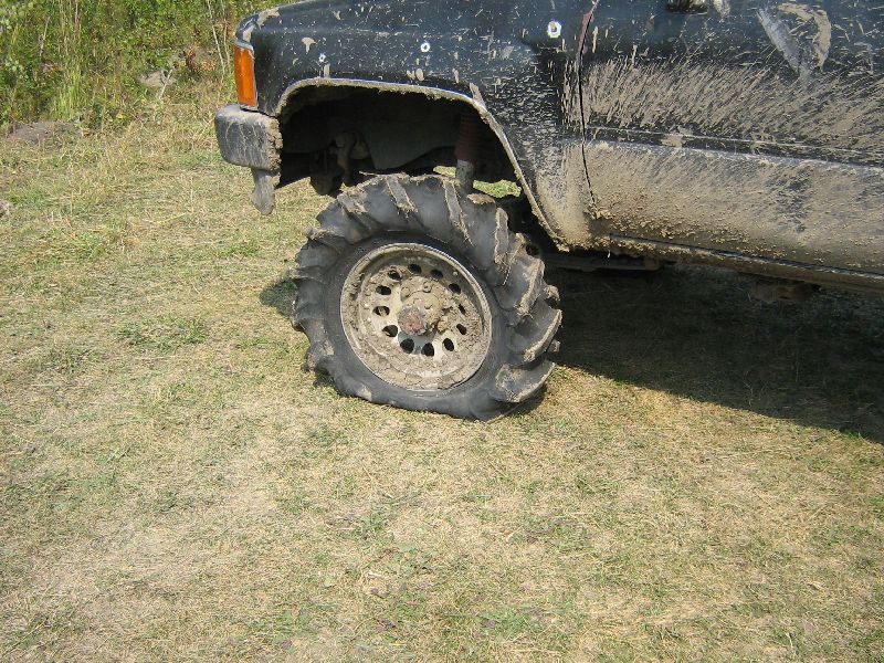 Muddy off-road tire on a black vehicle, front fender visible