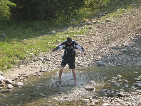 1995 Ford Bronco - A person enjoys a moment in a shallow, rocky stream surrounded by nature.