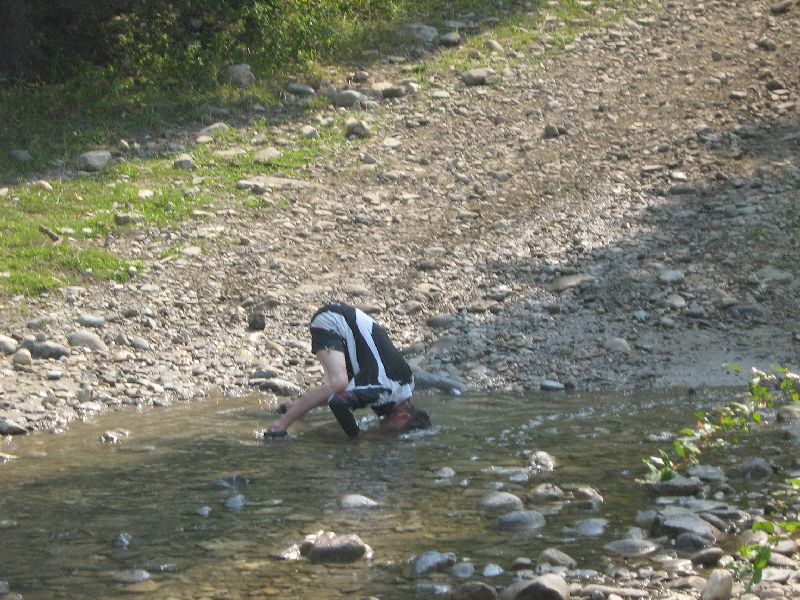 Person bending over in a rocky stream, with a "SUPER MOTORS" logo in the corner