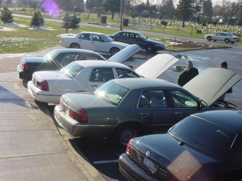 2003 Ford Crown Victoria - Several Ford Crown Victorias are parked in a lot, with at least two having their hoods open, suggesting a gathering or event.