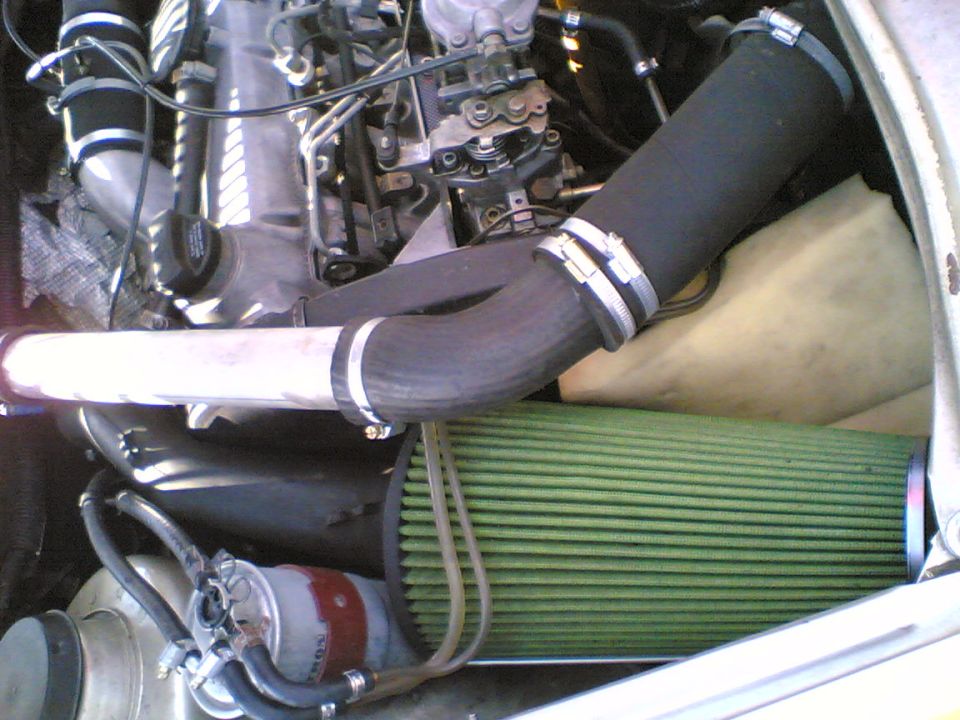 Diesel engine bay with green cone air filter, white intake pipe and T-bolt clamps over injection pump
