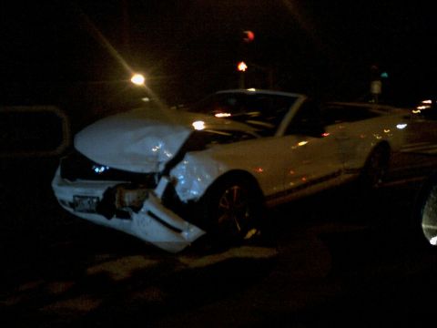 2001 Ford Crown Victoria - A white convertible sports car sustained significant front-end damage in an accident at night.