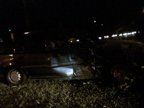 2001 Ford Crown Victoria - A dark sedan is seen at night with significant damage to its passenger side door and front quarter panel.