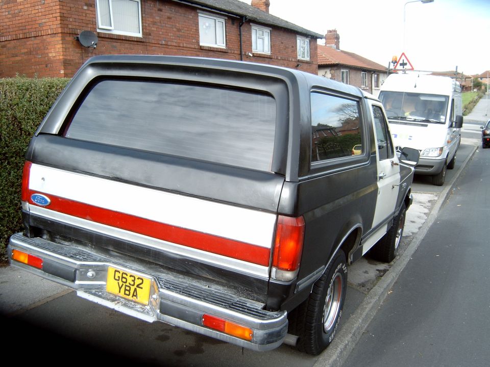 Black and white Ford Bronco with red stripe, rear view, parked on UK street, plate G632 YBA