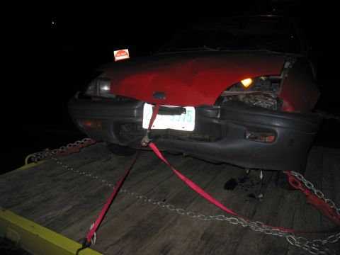 1991 Ford LTD Crown Victoria - Front view of a damaged red car being towed at night.