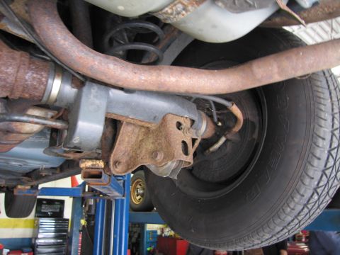 1991 Ford LTD Crown Victoria - Undercarriage view of a vehicle's rear axle and suspension system, showing rust and wear.