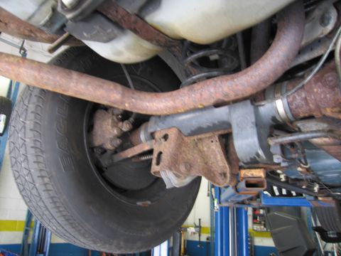 1991 Ford LTD Crown Victoria - The rear suspension and exhaust system of a vehicle are shown, with significant rust present on the components.
