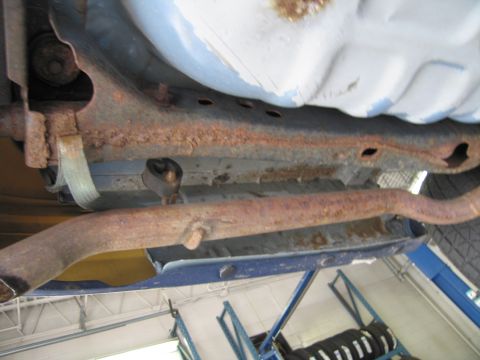 1991 Ford LTD Crown Victoria - The underbody of the vehicle shows significant rust on the frame and exhaust system.