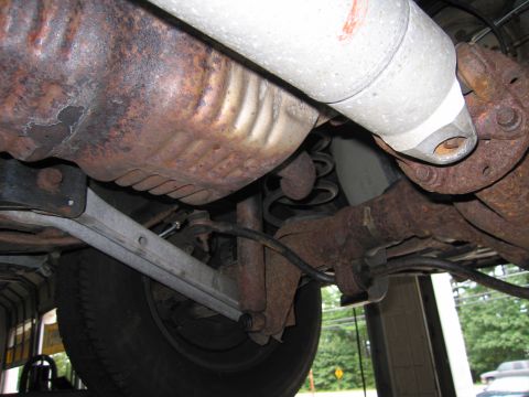 1991 Ford LTD Crown Victoria - Close-up view of the undercarriage, showing significant rust on the exhaust system and suspension parts.