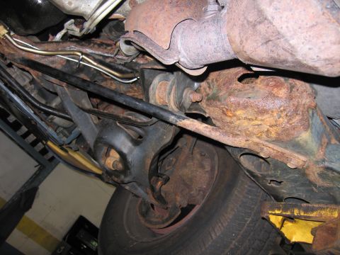 1991 Ford LTD Crown Victoria - The undercarriage of this vehicle shows significant rust on suspension parts and the exhaust system.