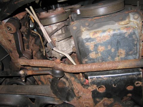 1991 Ford LTD Crown Victoria - Close-up view of heavily rusted engine and suspension components under a vehicle.
