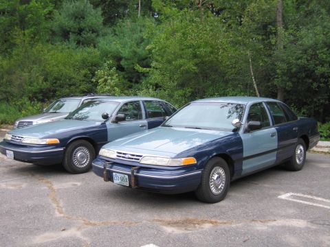 1991 Ford LTD Crown Victoria - Two Ford Crown Victoria sedans, one with a two-tone blue paint scheme, are parked side-by-side.