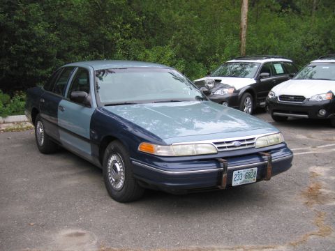 1991 Ford LTD Crown Victoria - A two-tone blue sedan parked in a lot with other vehicles visible in the background.