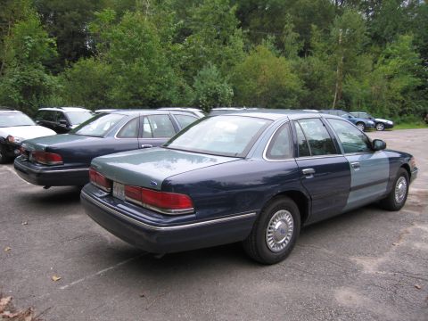 1991 Ford LTD Crown Victoria - Two Ford Crown Victorias are parked in a lot, one with a distinctive two-tone paint scheme.