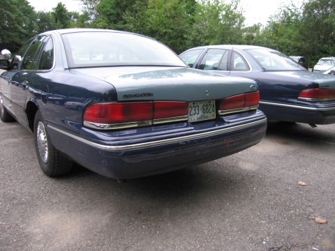 1991 Ford LTD Crown Victoria - Two blue Ford Crown Victoria LTD sedans are parked side-by-side on asphalt.