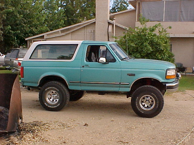 Teal 1994 Ford Bronco parked outside a house