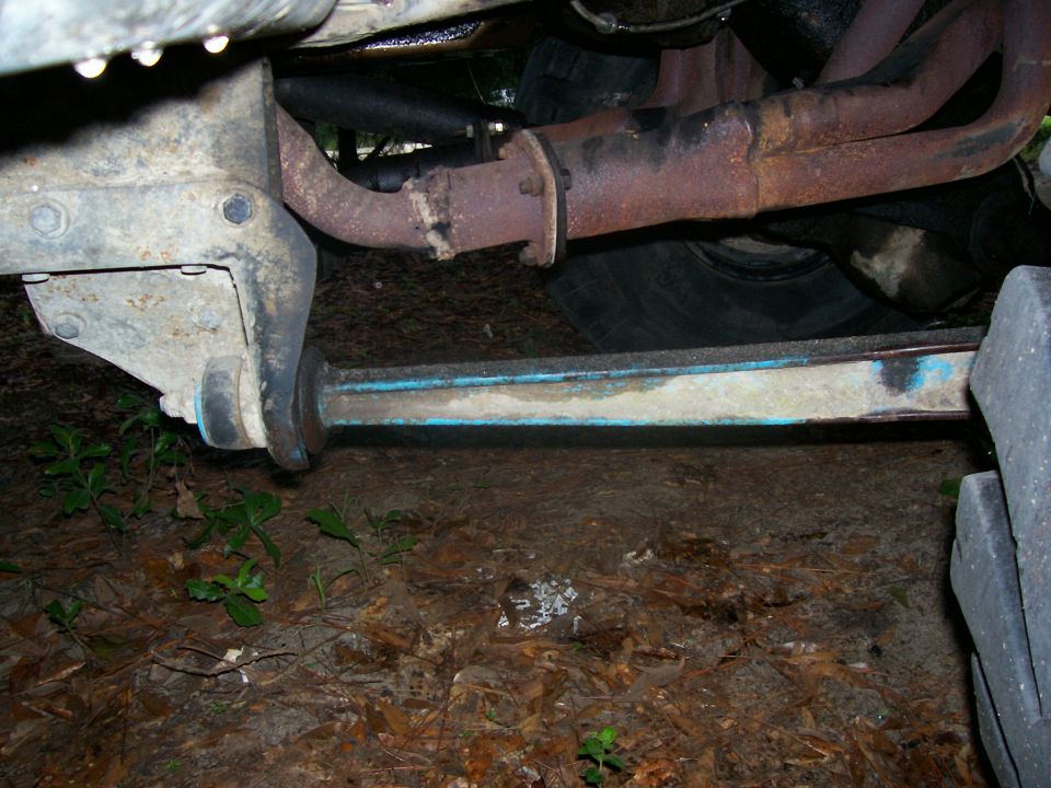 Underside of a vehicle showing rusty exhaust pipes and suspension components