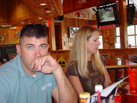 1986 Ford Mustang - A man and woman sit at a table in a restaurant, with a race playing on the television overhead.