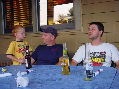 1986 Ford Mustang - Three people sit at a table outdoors, with drinks and napkins scattered across the blue tablecloth.