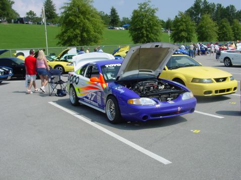 1986 Ford Mustang - A custom-painted Ford Mustang with its hood open is displayed at an outdoor car event.