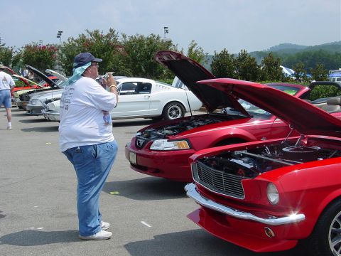1986 Ford Mustang - A red 1965 Ford Mustang convertible is displayed with its hood open at an outdoor car show.