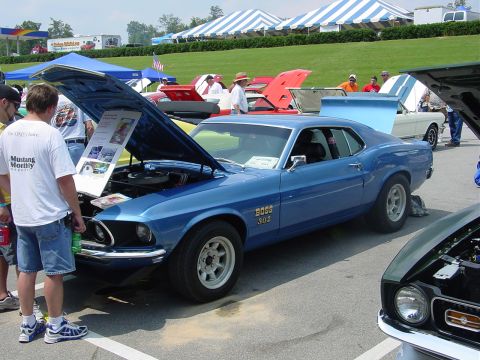 1986 Ford Mustang - A blue 1969 Ford Mustang Boss 302 is displayed with its hood open at a car show event.