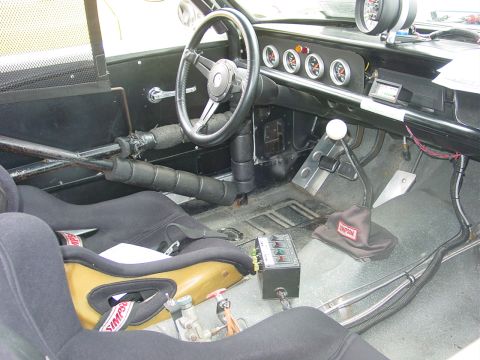 1986 Ford Mustang - The interior of a modified vehicle features racing seats, a roll cage, and a dashboard with multiple gauges.