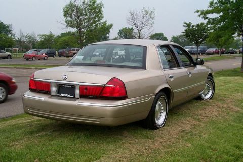 1999 Mercury Marquis - Rear view of a tan 1999 Mercury Grand Marquis sedan parked on a grassy area. The license plate is visible.