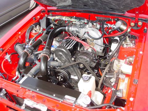 1986 Ford Mustang - Close-up view of a V8 engine bay, showing intake, battery, and wiring.
