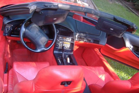 1994 Chevrolet Corvette - The interior of a red 1994 Chevrolet Corvette convertible is visible, with a focus on the dashboard and seating.