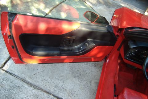 1994 Chevrolet Corvette - The interior door panel of a red 1994 Chevrolet Corvette is visible.