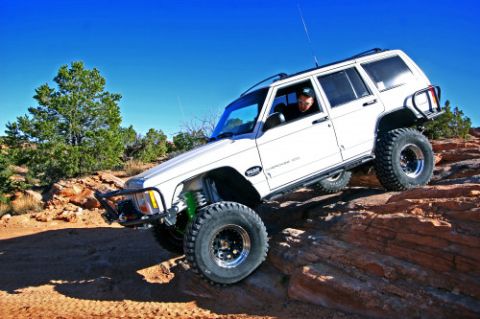 1997 Jeep TJ - A white Jeep Cherokee XJ navigates a rocky incline under a clear blue sky.