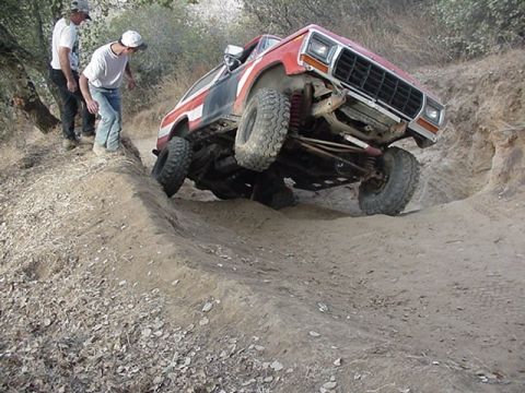 1979 Ford Bronco - This modified 1979 Ford Bronco is shown tackling a challenging off-road obstacle with two onlookers.