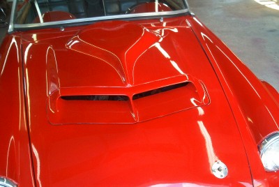 1972 Ford Ranchero - Close-up of a red car's hood a distinctive scoop and visible headlight detail.