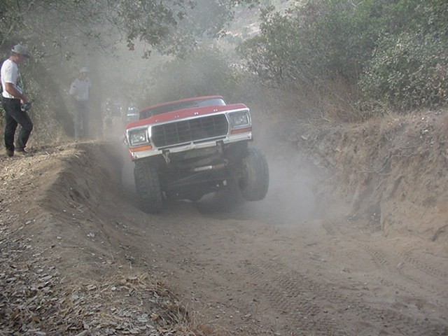 red SUV kicking up dust on a dirt trail