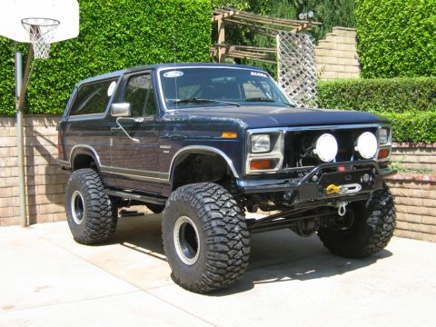 1985 Ford Bronco - This lifted Ford Bronco sits parked in a driveway with a basketball hoop nearby.