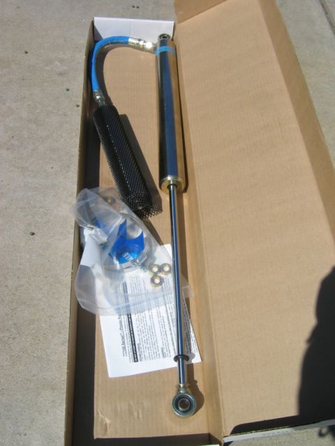 1985 Ford Bronco - A shock absorber assembly, including a blue hose and protective sleeve, is shown inside its packaging.