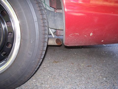 1999 Ford Crown Victoria - A portion of a red vehicle's side is visible, with a tire and exhaust pipe in the foreground.