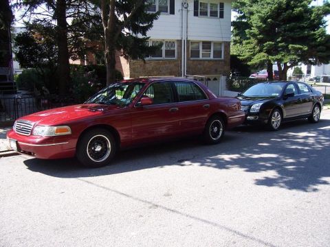 1999 Ford Crown Victoria - Two sedans parked on a residential street.