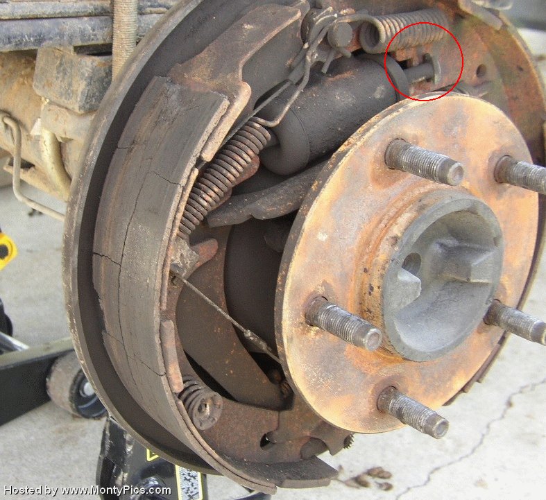 Rear drum brake assembly with cracked brake shoes and rusty components