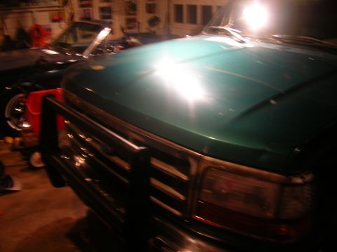 1996 Ford Bronco - A green 1992 Ford F-Series truck is parked in a garage, showing its front end with a brush guard.