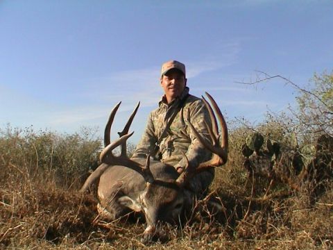 1986 Ford Bronco - A successful hunter poses with a large buck after a hunt in a dry, brushy area.