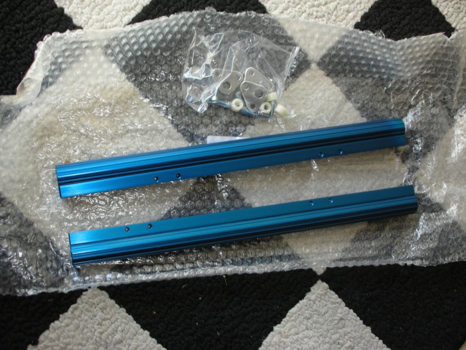 Pair of blue anodized aluminum rails and hardware bag on bubble wrap