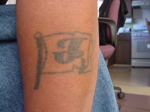 1979 Ford Bronco - Close-up of a tattoo on an arm, depicting a flag with a letter 'F' design.