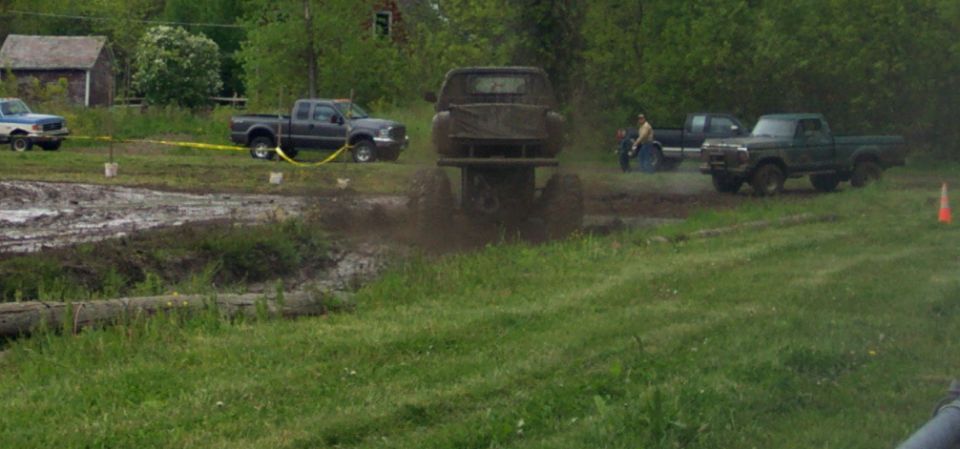 Mud bogging scene with trucks in mud and grass
